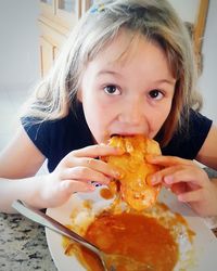 Close-up portrait of smiling girl eating food at home