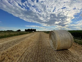 Hay bales on field against sky