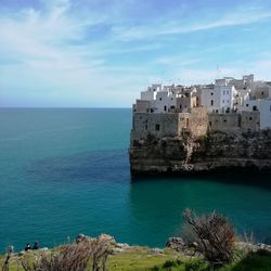 Sea by buildings against sky