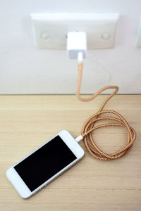 High angle view of smart phone being charged at home