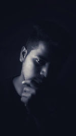 Close-up portrait of young man over black background