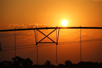 Silhouette electricity cables against sky during sunset