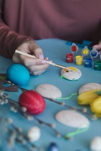 Midsection of person hands painting eggs on table