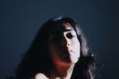 Close-up portrait of young woman against gray background