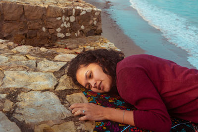 Woman leaning on rock at beach