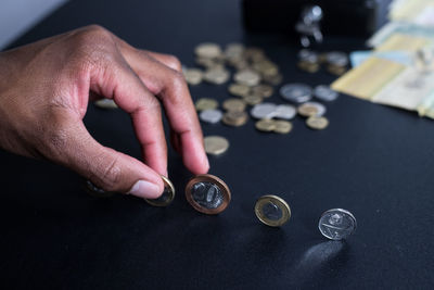 Midsection of person holding coins on table