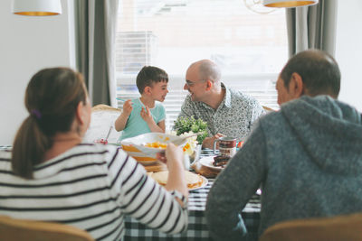 Rear view of people eating food at home