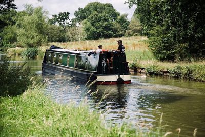 People in boat on river against trees