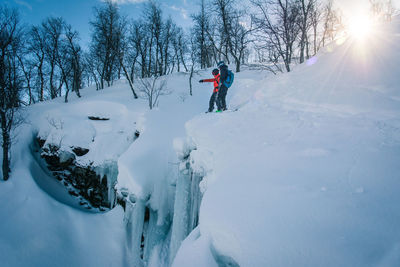 Men skiing on snow against bare trees