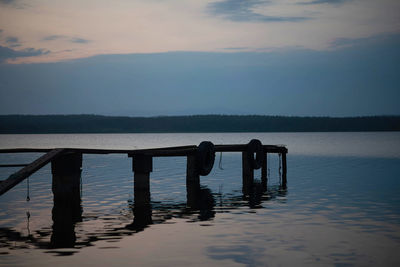 Wooden pier on lake against sky during sunset