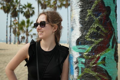 Portrait of young woman wearing sunglasses standing at beach