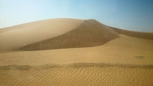 Scenic view of sand dunes against clear sky