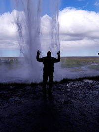 Rear view of man standing against geyser