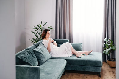 Woman drinking mug of coffee in cozy home atmosphere in the morning. real middle age plus size