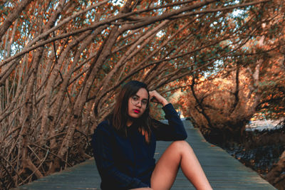 Portrait of beautiful woman standing by tree