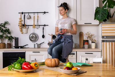 Young and beautiful housewife woman cooking in a white kitchen