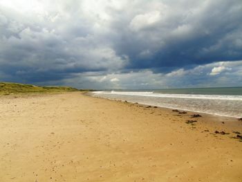 Scenic view of beach against cloudy sky