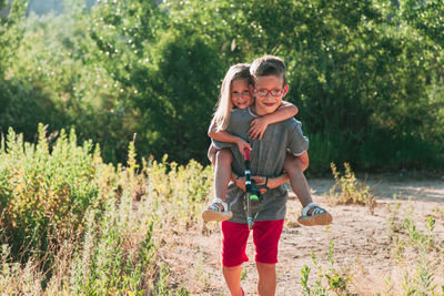 Portrait of boy piggybacking sister on field