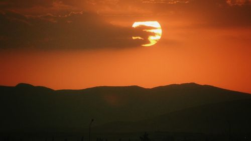 Scenic view of silhouette mountains against orange sky