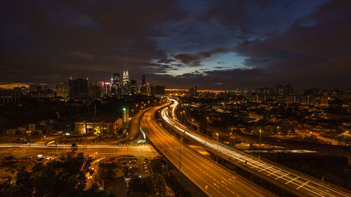 High angle view of light trails on street amidst buildings at night