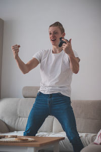 Young man using mobile phone on sofa at home