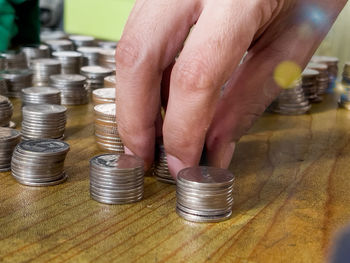 Close-up of a hand holding glass of coins on table