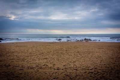 Scenic view of beach against cloudy sky