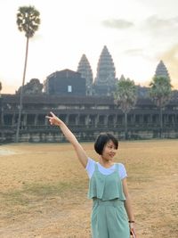 Portrait of smiling woman standing against built structure