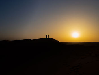 Scenic view of beach against clear sky during sunset