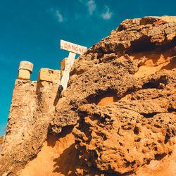 Low angle view of text on rock against sky