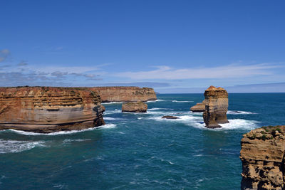 Rock formations in sea against blue sky