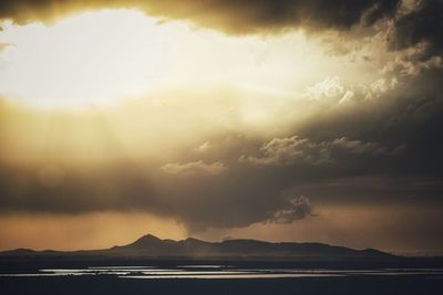 Scenic view of beach against cloudy sky during sunset