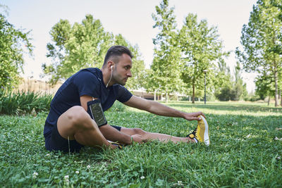 Sportsman stretching muscles sitting on the grass