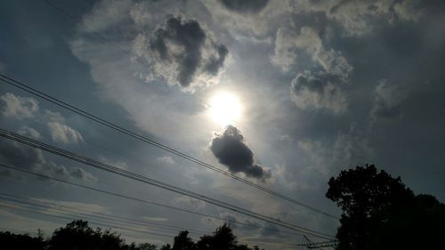 Low angle view of electricity pylon against cloudy sky
