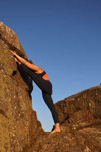 Rear view of man standing on mountain against clear blue sky