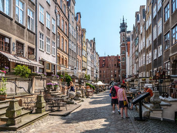 People on footpath amidst buildings in city