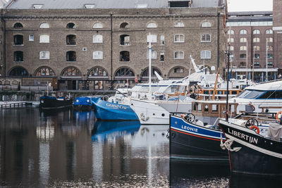 Boats moored in canal by buildings in city