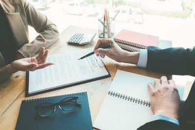 Cropped hands of businessman discussing with male colleague in office