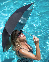 High angle view of woman holding umbrella in swimming pool