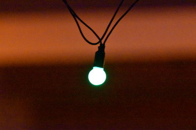 Low angle view of illuminated light bulb hanging on ceiling