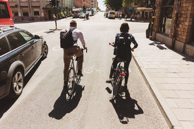 Rear view of people riding bicycle on street