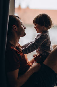 Side view of mother and daughter sitting on floor