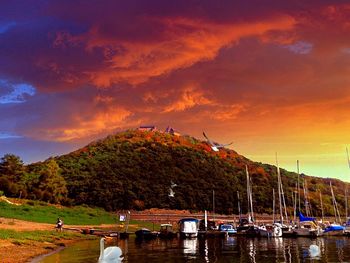 Sailboats moored on lake against sky during sunset