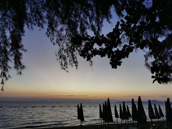 Silhouette wooden posts in sea against sky at sunset