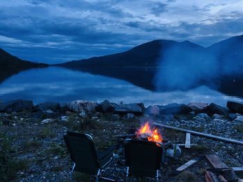 View of bonfire by lake during dusk