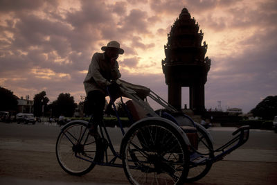 Man riding bicycle on street against sky