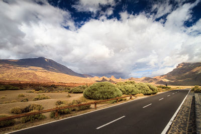 Road leading towards mountains against sky