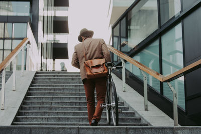 Rear view of man walking on staircase
