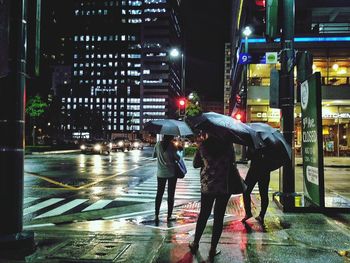 People walking on wet street at night