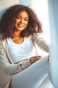 Portrait of young woman sitting against white background